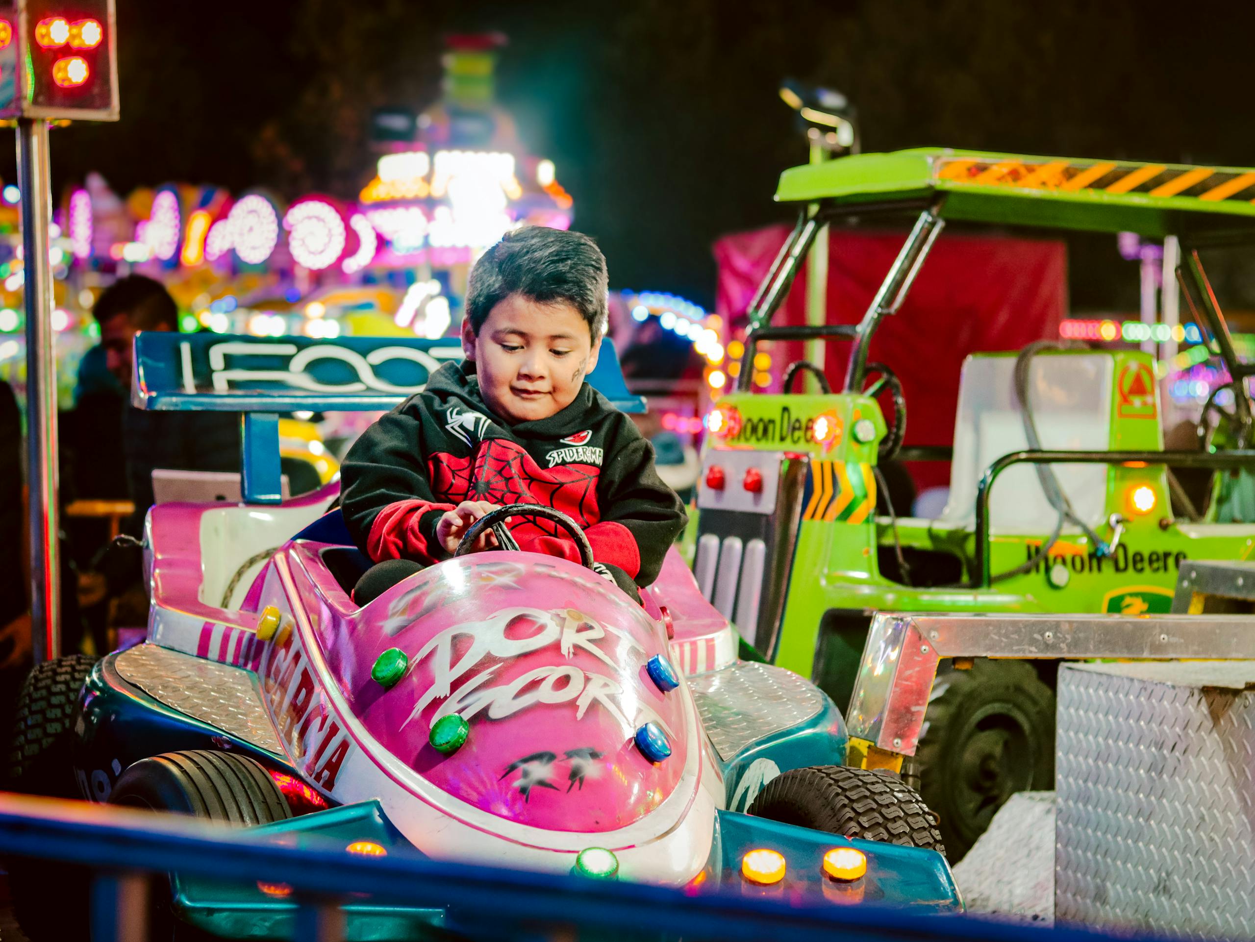 Adorable child enjoys colorful bumper car ride at a lively night fair, surrounded by bright lights and attractions.